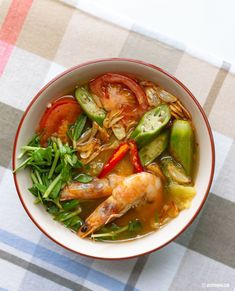 a bowl filled with shrimp and vegetables on top of a checkered table cloth