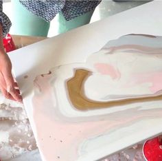 a person is painting on a large piece of white and gold art work with acrylic paint