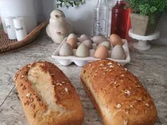 two loaves of bread sitting on top of a counter next to an egg tray