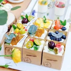 small boxes filled with different types of fruit on top of a wooden table next to cups and saucers