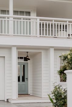 a white house with a blue door and balcony