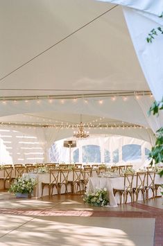 the inside of a tent with tables and chairs set up for an outdoor wedding reception