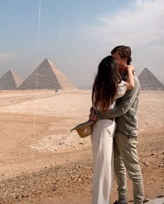 a man and woman kissing in front of the pyramids