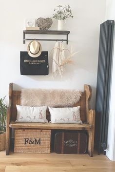 a wooden bench sitting next to a wall filled with plants and pillows on top of it