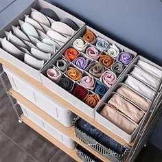 an organized drawer with folded towels and folded socks in it's trays on the floor