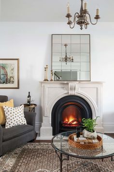 a living room filled with furniture and a fire place under a mirror on the wall