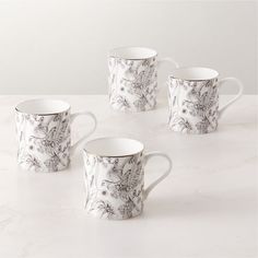 four white and black coffee mugs sitting on top of a marble countertop next to each other