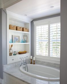 a bathroom with white cabinets and marble counter tops, along with a large bathtub