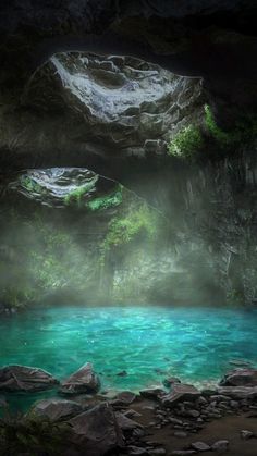 the water is very blue and green in this cave with large rocks on either side