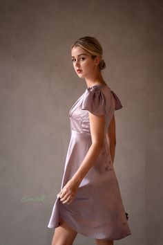 "This luxury lavender silk dress design is perfect for any occasions. 100 % designed and handmade by Emsilk. I am pleased to offer your garments made to measure at no extra cost. * Detail: - Deep V neckline with silk covered buttons detail - Fitted waist - Small puffed cap sleeves - Invisible zipper on the back. - Above the knee length -Best quality silk, 100 % pure 19mm Mulberry Silk which is made using traditional weaving techniques. This silk hugs your body tenderly and you will not want to t Elegant Lavender A-line Dress, Feminine Satin Knee-length Mini Dress, Feminine Satin Mini Dress With Short Sleeves, Feminine Short Sleeve Satin Mini Dress, Feminine Silk Knee-length Mini Dress, Feminine Fitted Silk Knee-length Dress, Feminine Knee-length Silk Mini Dress, Elegant Mauve V-neck Mini Dress, Elegant Purple Satin Mini Dress