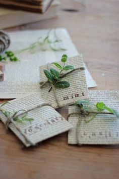 four pieces of paper with green leaves on them sitting on top of a wooden table