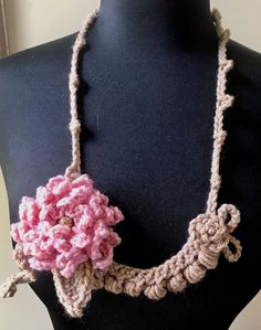 a crocheted necklace with a pink flower on it