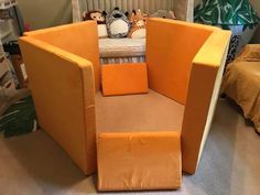 an orange chair sitting in the middle of a room next to a bed and stuffed animals