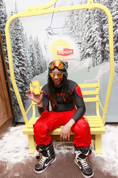 a man sitting on a yellow bench with skis and goggles over his eyes