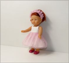 a doll is standing against a white wall