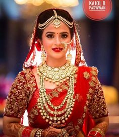 a woman in a red and gold bridal outfit looking at her cell phone