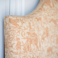 an orange and white pillow sitting on top of a wooden table next to a wall