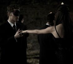 a man in a suit and sunglasses is holding out his hand to a woman with blindfolds