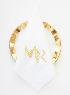 a napkin with the initials mr and mrs on it sitting on top of a gold plate