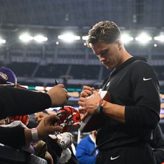 a man signing autographs for fans at a football game