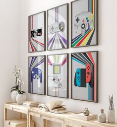 four framed video game posters hang on the wall above a table with books and vases