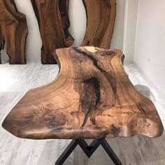 a wooden table sitting on top of a black metal stand in front of some wood sculptures