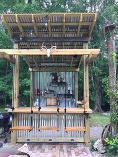 an outdoor bar made out of wooden pallets and barstools with deer heads hanging from the roof