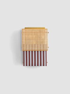 a piece of woven material hanging on the wall next to a wooden frame with stripes