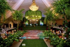 the inside of a tent decorated with greenery and chandeliers