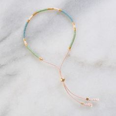 the multi - colored beaded bracelet is on top of a marble surface