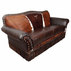 a brown leather couch with fringe trim and cowhide pillows on the armrests