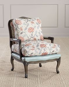 a chair with a floral upholstered back and arm rests on a carpeted floor