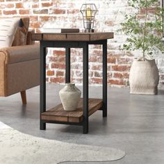 a small table with a vase on it in front of a couch and brick wall