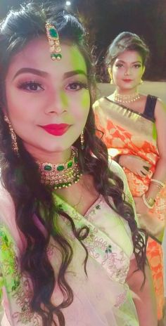 a woman in a green and white sari with two other women standing behind her