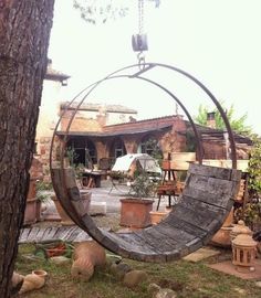 an old tire swing sitting in the middle of a yard next to potted plants