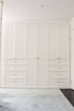 an empty room with white cabinets and blue rug on the floor in front of it