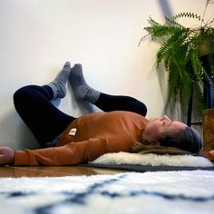 a woman is laying on the floor with her feet up in the air and she has her eyes closed