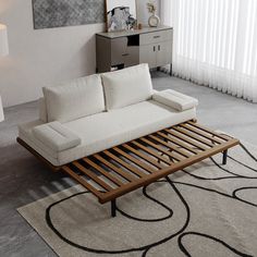 a white couch sitting on top of a living room floor next to a lamp and rug