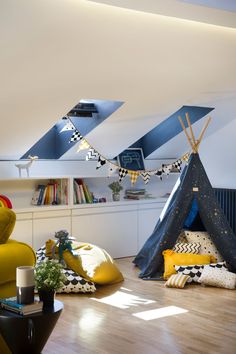 a teepee tent in the middle of a living room with pillows on the floor