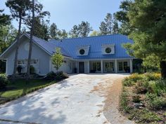 a white house with a blue roof surrounded by trees