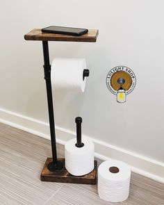 two rolls of toilet paper sitting on top of a wooden stand next to a phone