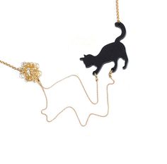 a black cat on a gold chain with a flower in it's tail and a ball of yarn hanging from the back