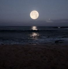 the full moon is shining over the ocean