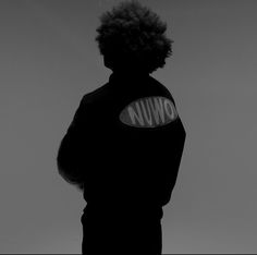 a man with curly hair standing in front of a black and white background wearing a snowboard jacket