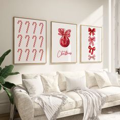 three christmas pictures hang on the wall above a couch in a living room with white furniture