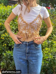 a woman standing in front of some bushes wearing a crop top with chains on it