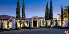 the front entrance to a home with trees and bushes on either side of the house