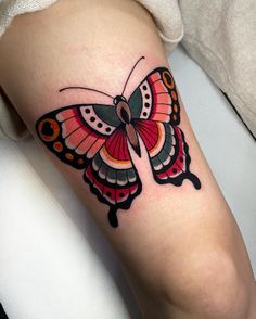 a colorful butterfly tattoo on the right thigh and lower leg, with black dots around it