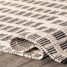 a rug with black and white designs on it sitting on a wooden floor next to a wood floor