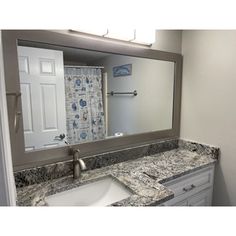 a bathroom sink sitting under a large mirror next to a white cabinet and counter top